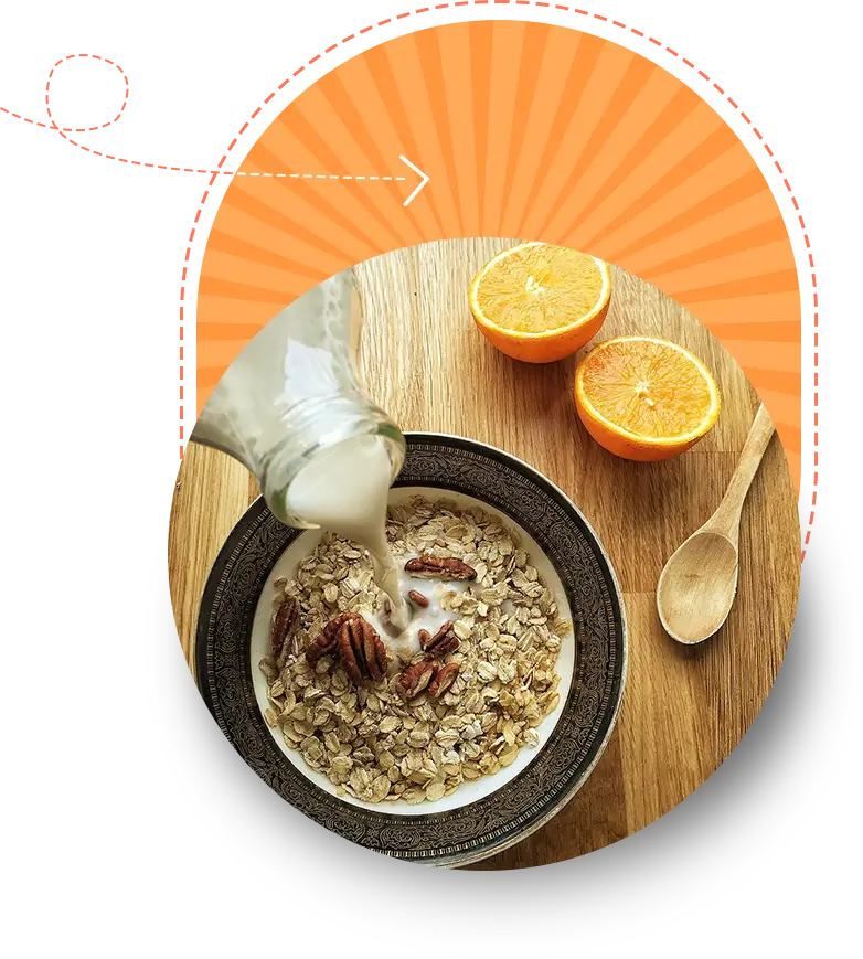 Milk being poured into a bowl of cereal with pecans, next to halved oranges on a wooden table, against an orange graphical background.